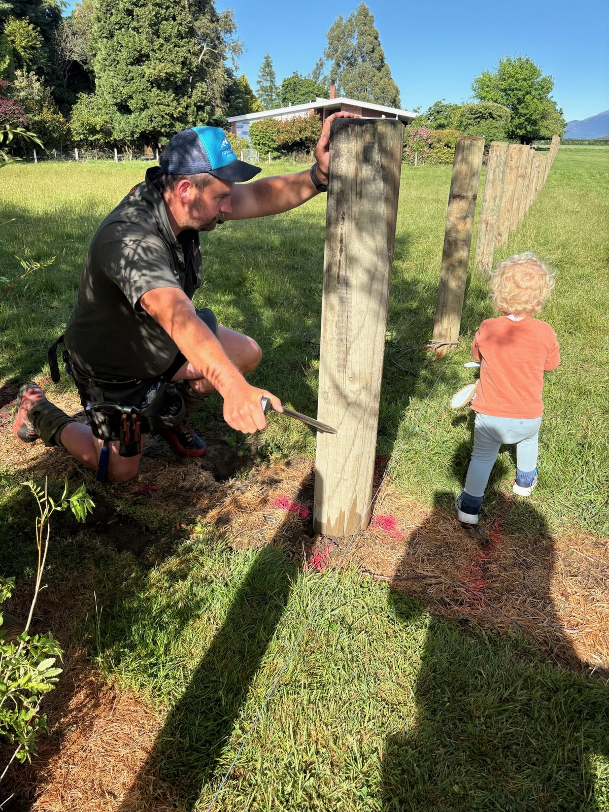 Mark from Jorgensen Fencing setting a post on site, with his toddler alongside